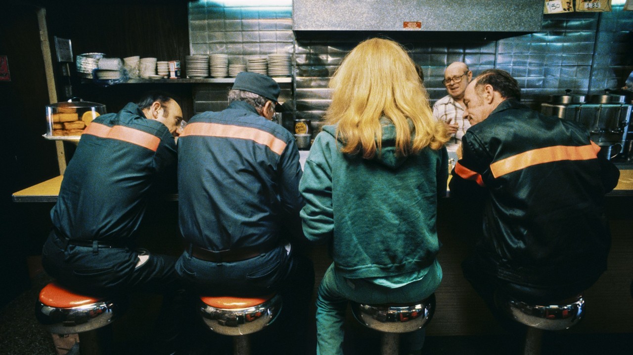 Four people sitting on bar stools in a diner